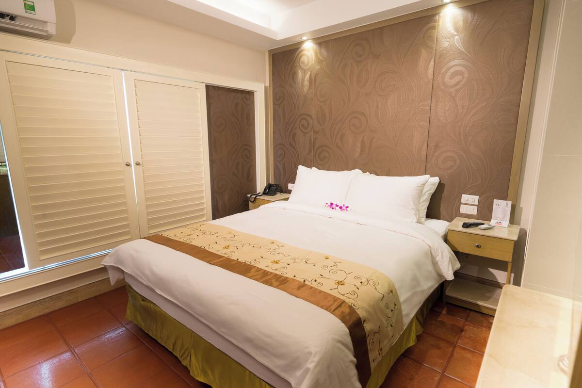 Ein Hotelzimmer mit Bett, Nachttisch, Kleiderschrank und Fenster.