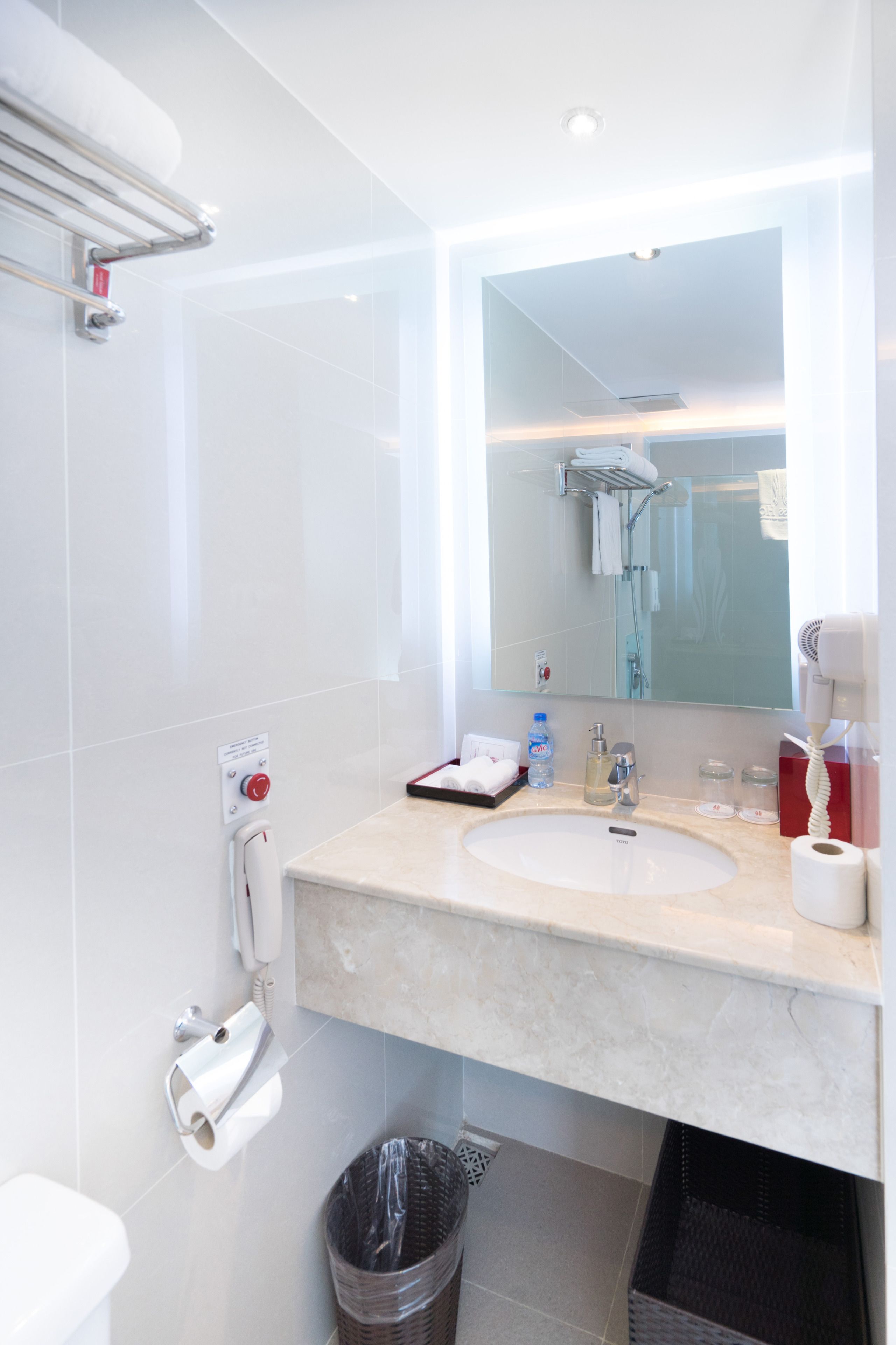 Een moderne badkamer met een grote spiegel, een wastafel, een douche en een prullenbak.