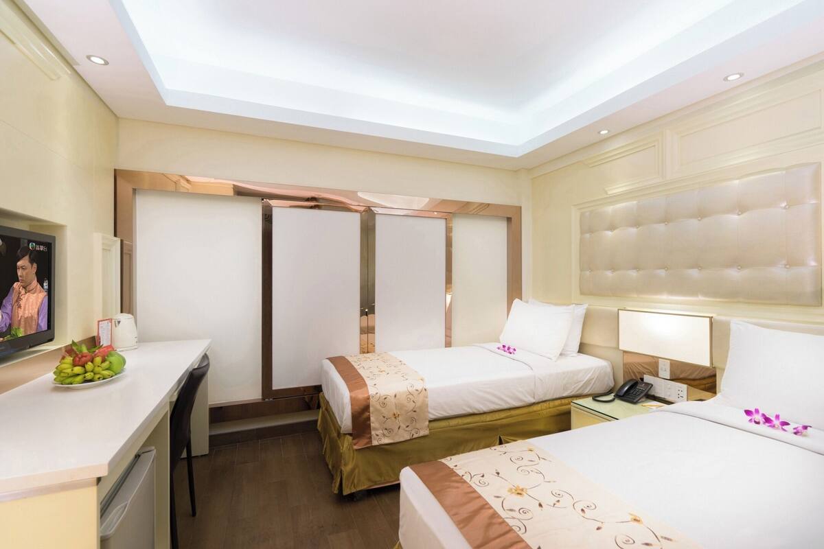 Ein Hotelzimmer mit zwei Betten, einem Schreibtisch, einem Fernseher und einer Minibar.