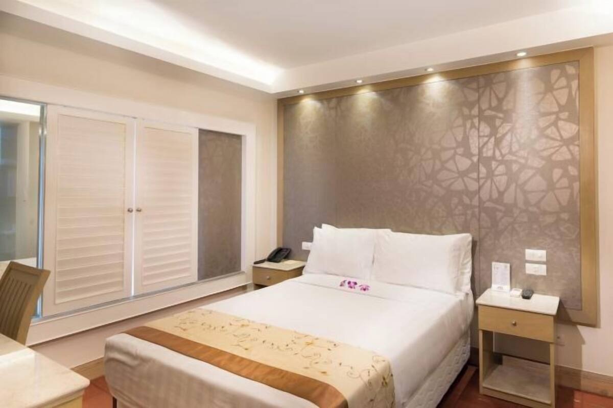 Ein Hotelzimmer mit Bett, Nachttischen, einem Schreibtisch und einem Kleiderschrank.