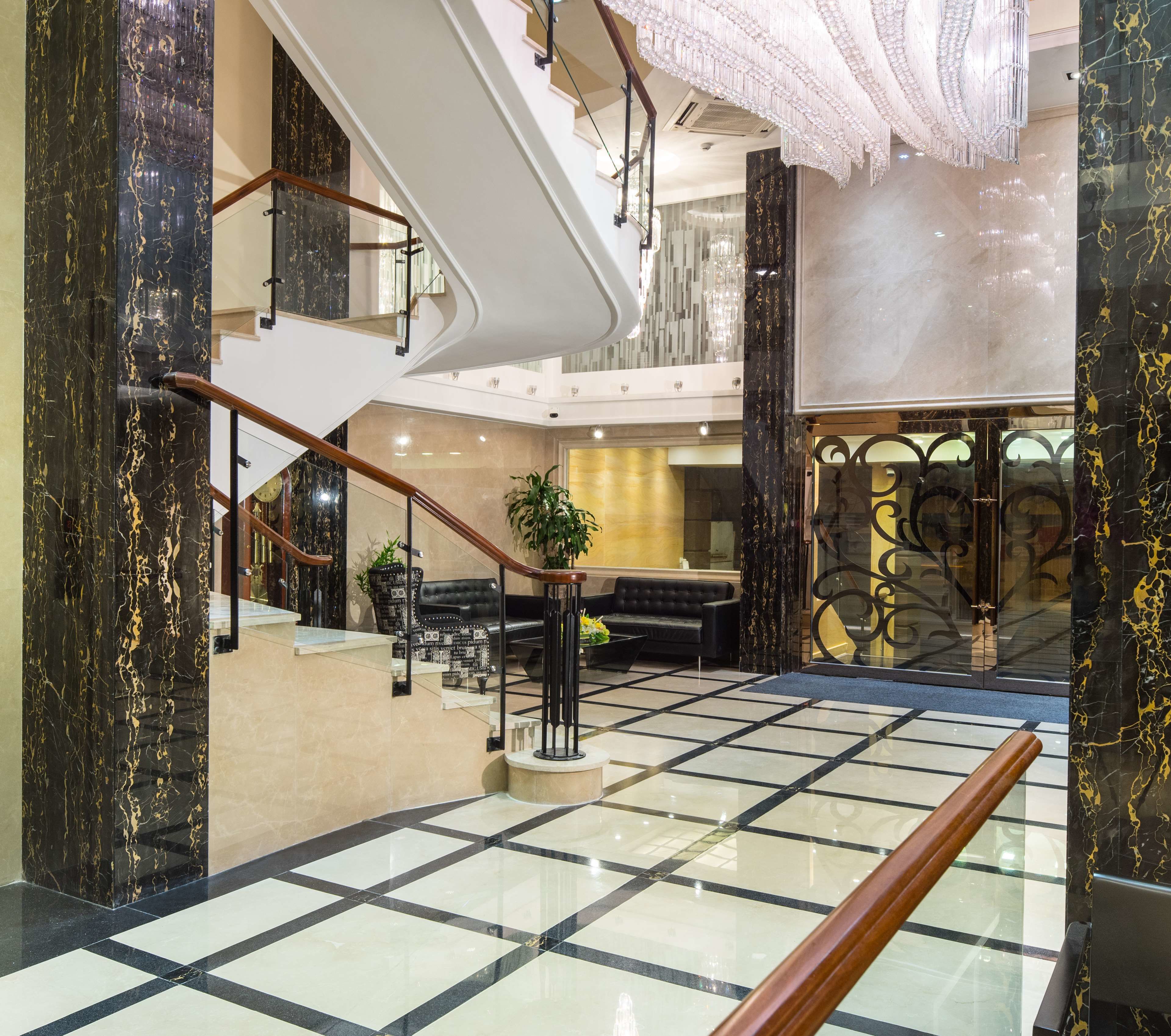 Un lobby amplio con suelo de mármol, una escalera y un área de descanso con sofá y mesa de centro.