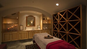 A spa room with a massage table, wooden cabinets, a mirror, and a wine rack. - The Inn at Solitude (Solitude)