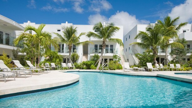 A pool area with lounge chairs and palm trees. - Santa Maria Suites (Key West)