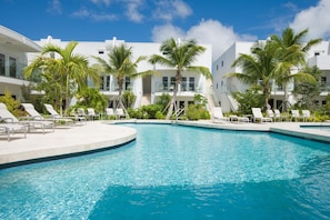 A pool area with lounge chairs and palm trees.