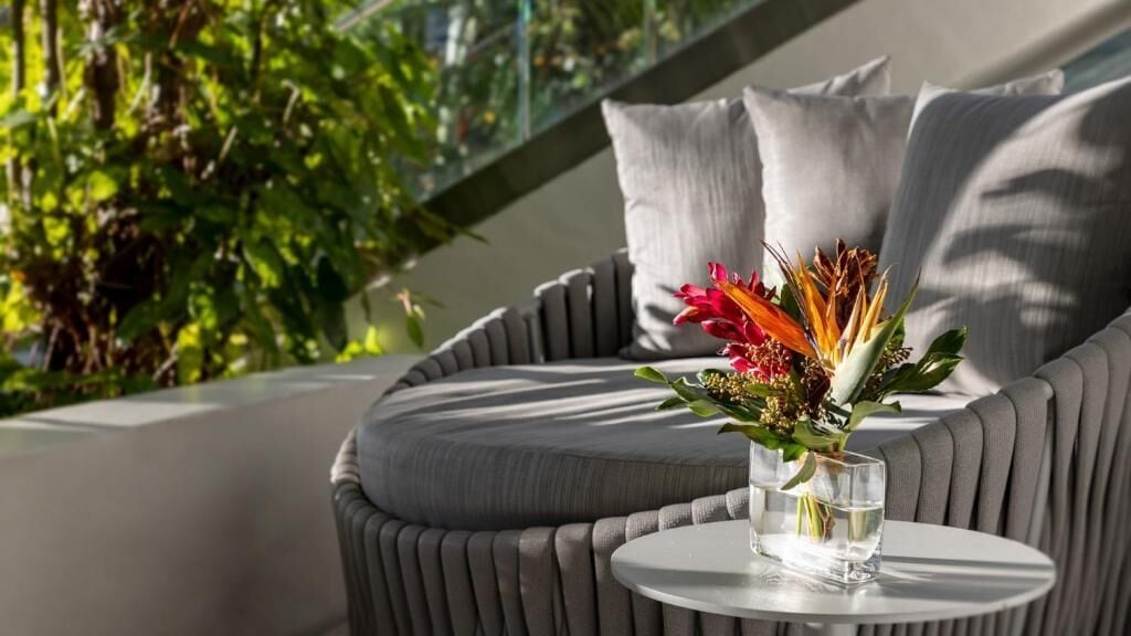 A modern outdoor seating area with a cushioned sofa and a small round table.