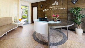 A reception area with a modern design, featuring a reception desk, a sofa, and a potted plant. - Santa Maria Suites (Key West)