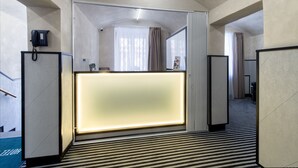 Zona de recepción de hotel con diseño moderno, que incluye un mostrador, un teléfono y un espejo.