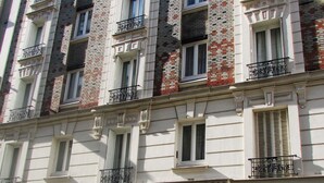 Un edificio de varios pisos con fachada de ladrillo, múltiples balcones y entrada a nivel de calle.