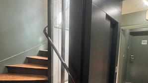 Una escalera de madera con barandilla negra que lleva a una puerta con el número 305.