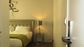 Una habitación de hotel con una cama, una mesita de noche con una lámpara y una puerta.