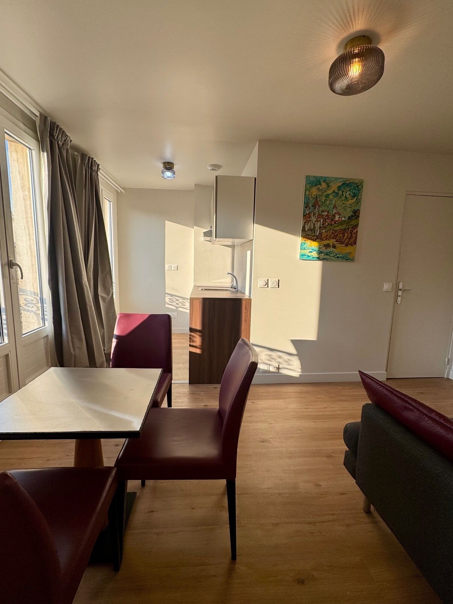 Een modern interieur met een eethoek, een bank, een keuken en een schilderij aan de muur.