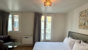 Une chambre d’hôtel avec un grand lit, une table basse en verre, un canapé et un tableau au mur.