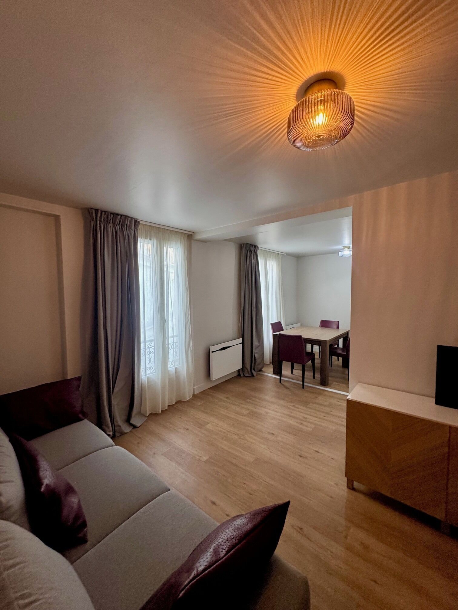 Ein modernes Wohnzimmer mit einer Couch, einem Esstisch und einer Deckenleuchte.