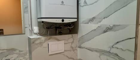 A bathroom with a white toilet, a sink, and a wall-mounted heater.