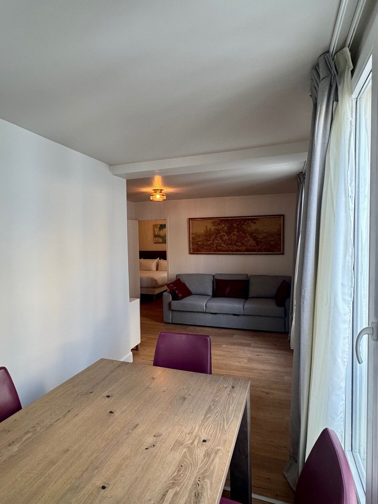 Un comedor con una mesa y sillas de madera, un sofá y un cuadro en la pared.