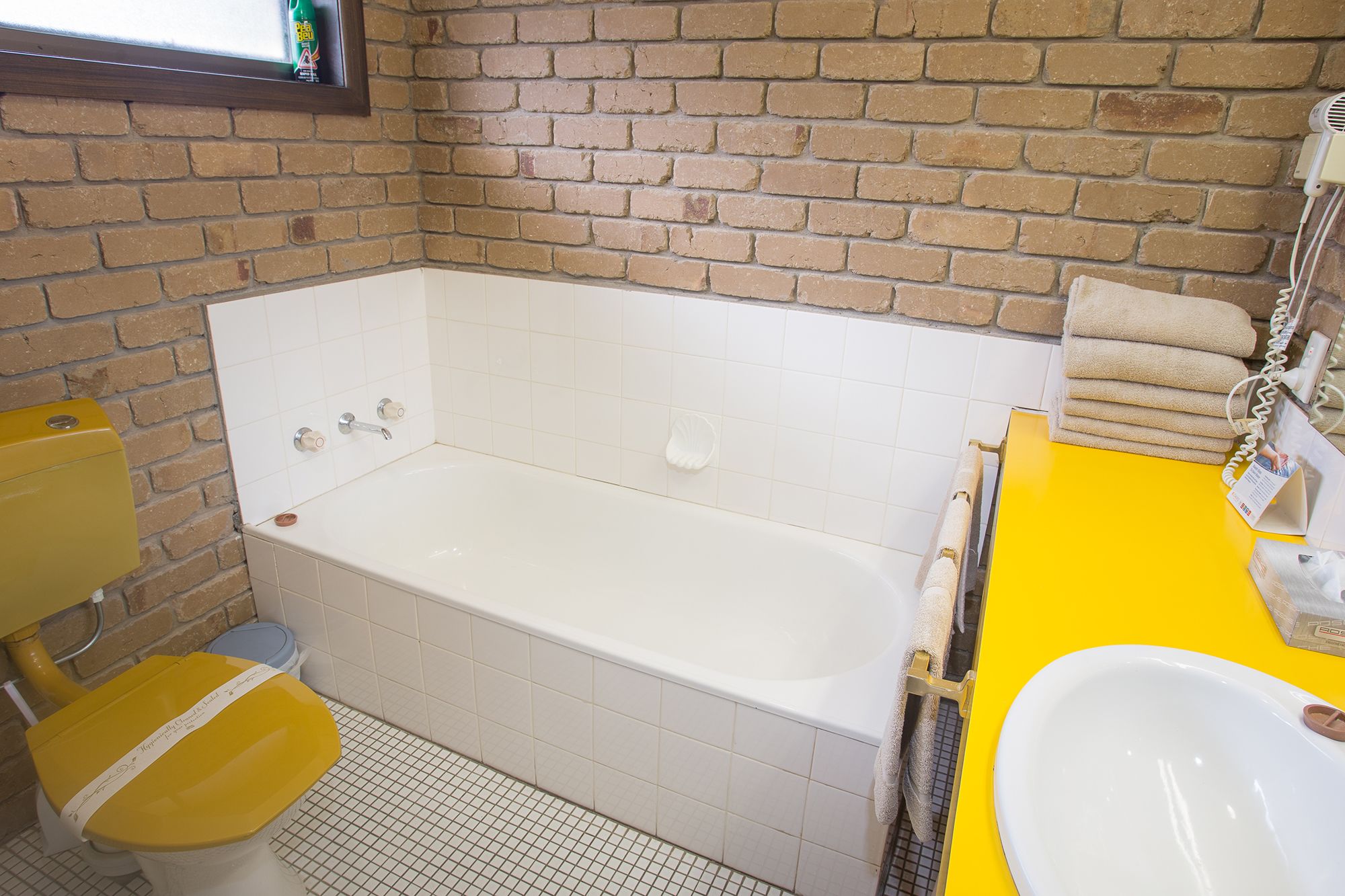 A bathroom with a bathtub, yellow sink, and a toilet.