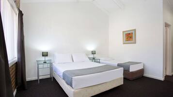 A hotel room with two beds, a small table, and a nightstand with lamps.