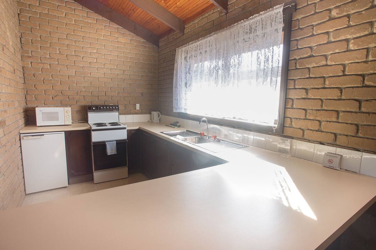 A compact kitchen with a microwave, stove, and sink.