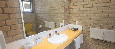 Un baño con encimera amarilla, un lavabo blanco y un espejo grande.