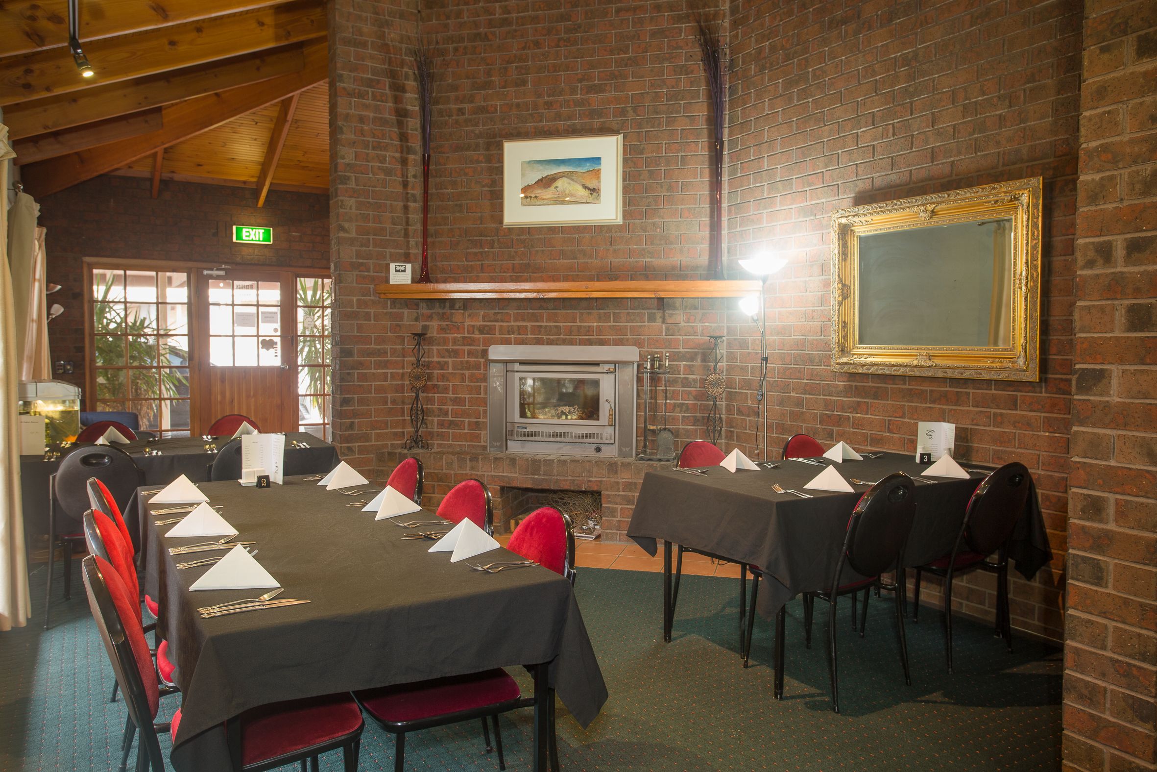A conference room with brick walls, a fireplace, and a large framed mirror.