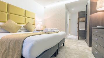A neatly made bed with a headboard, a bedside table with a lamp, and a set of folded towels.