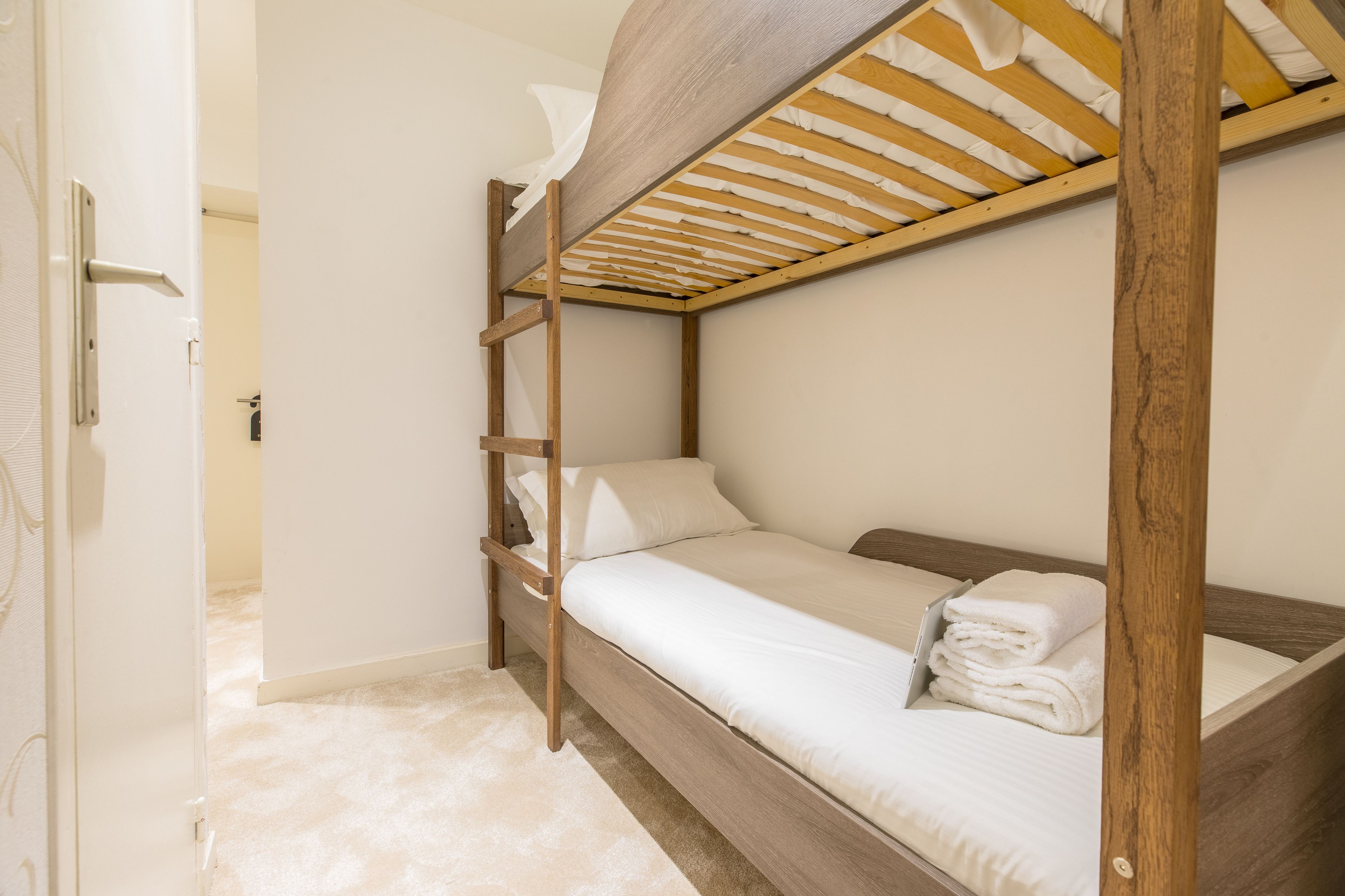 Una litera con estructura de madera y ropa de cama blanca.