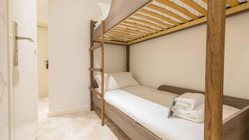 A bunk bed with a wooden frame and white bedding.