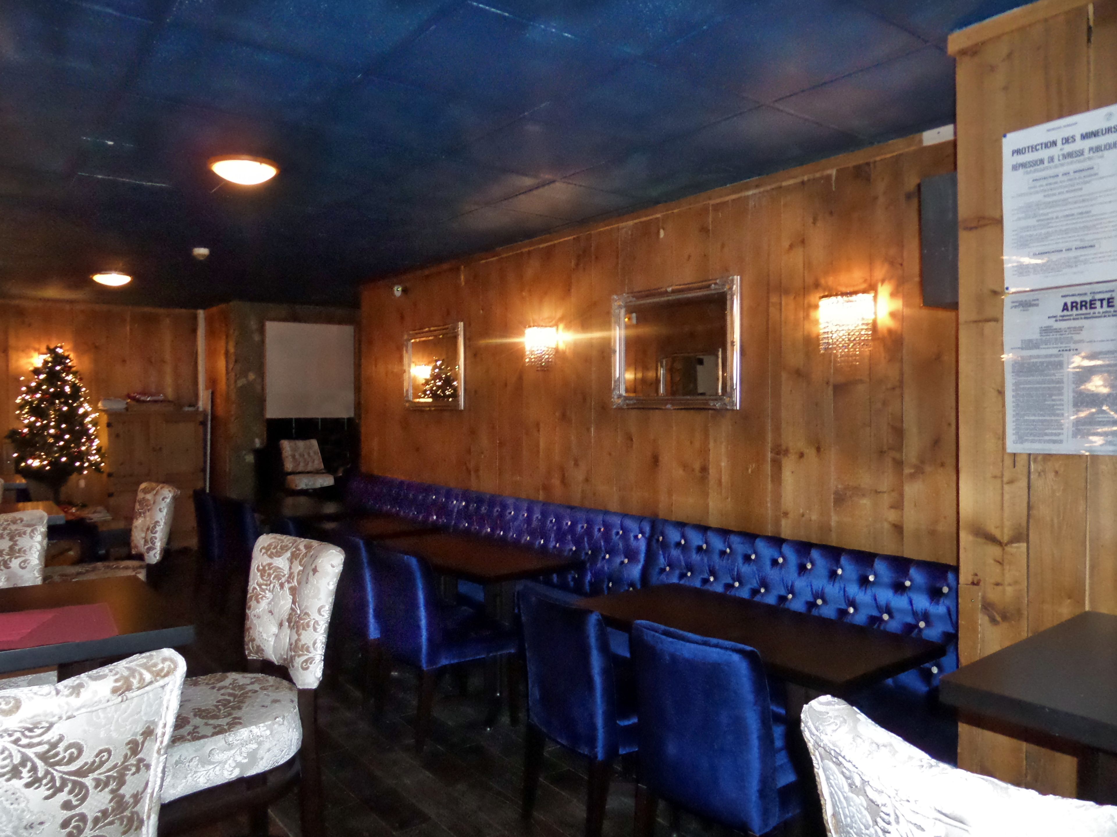Un ristorante con pareti in legno, sedute imbottite blu e un albero di Natale.