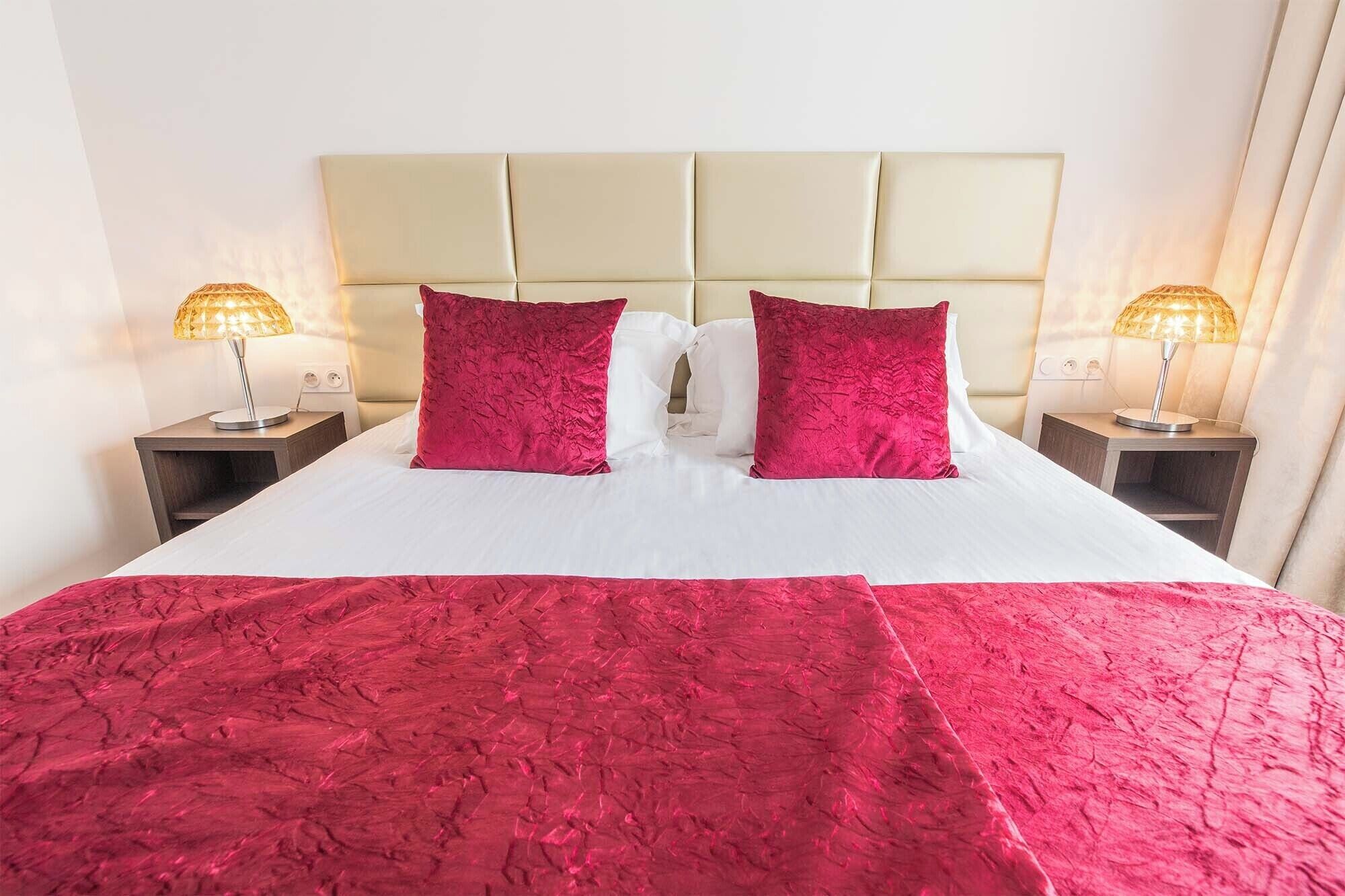 Una habitación de hotel con una cama grande, dos mesitas de noche y dos lámparas.