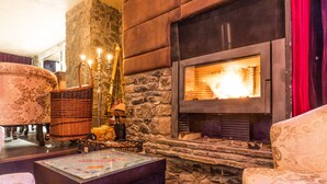 Una habitación acogedora con chimenea de piedra, un sofá mullido, una cesta de mimbre y una mesa de centro de vidrio.