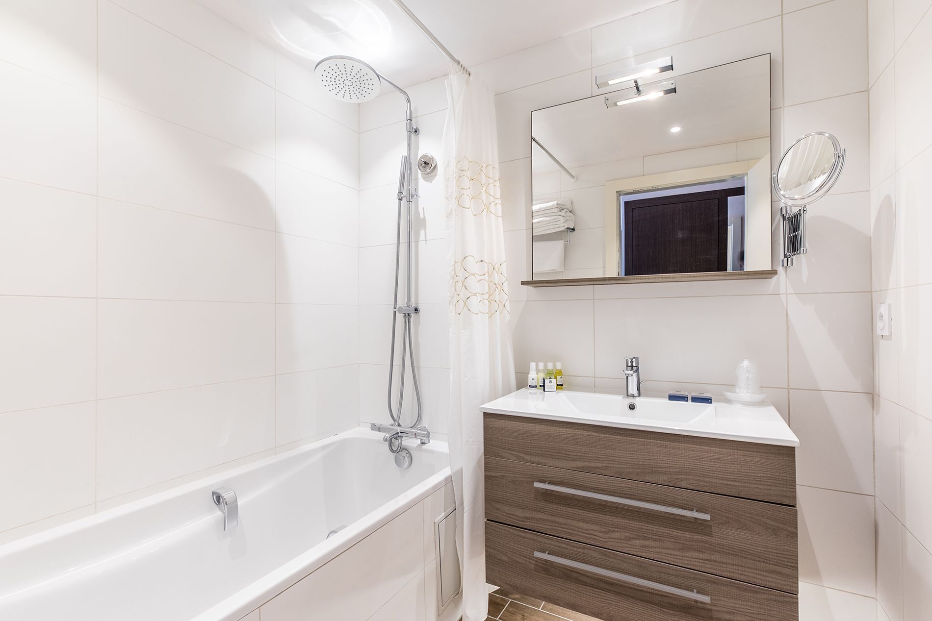 Ein modernes Badezimmer mit einer Badewanne, einer Dusche, einem Waschbecken mit Spiegel und Pflegeprodukten.