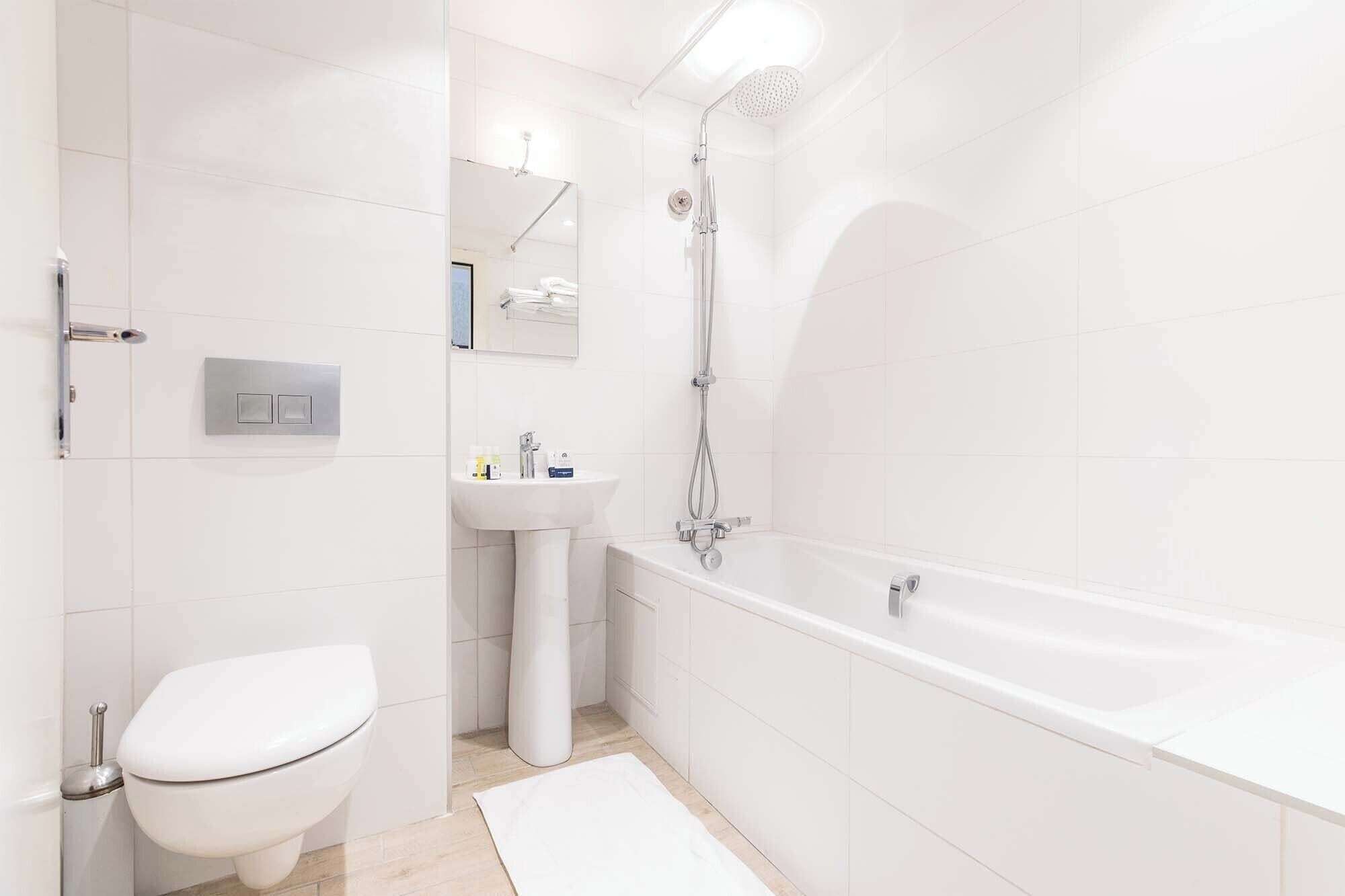 A modern bathroom with a toilet, sink, and bathtub.