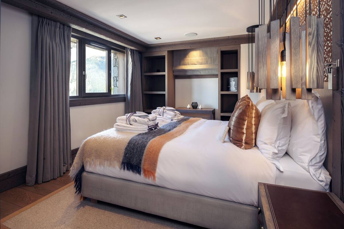 Een hotelkamer met een groot bed, een houten hoofdbord, een nachtkastje en een inbouwkast met boeken.