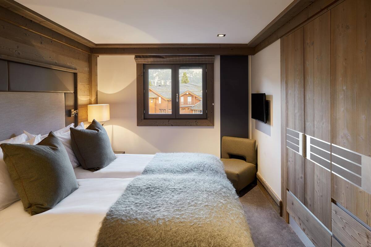 Een slaapkamer met een groot bed, een raam met uitzicht, een televisie en houten lambrisering.