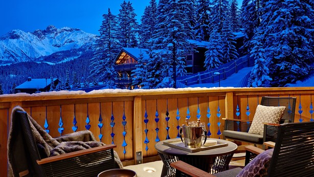 A cozy outdoor seating area with a view of snow-covered mountains and a cabin. - Six Senses Residences Courchevel (Courchevel)