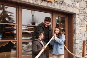 A family standing in front of a building with large windows and stone walls. - Six Senses Residences Courchevel (Courchevel)