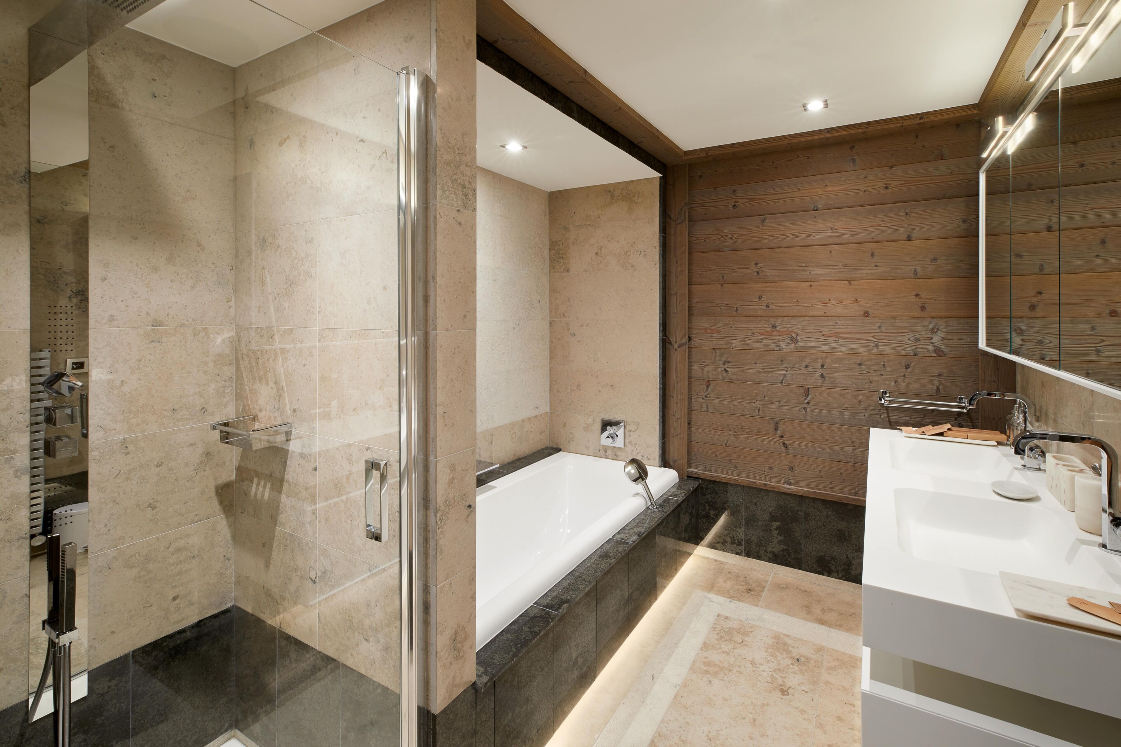 Un baño moderno con ducha de vidrio, bañera independiente y tocador blanco con espejo.
