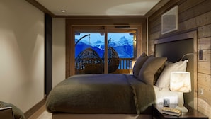 A bedroom with a large bed, a nightstand, a lamp, and a view of mountains through a window. - Six Senses Residences Courchevel (Courchevel)