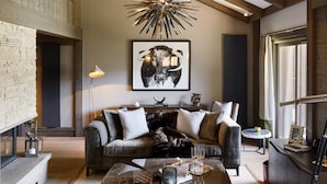 A spacious living room with a high ceiling, exposed wooden beams, a modern chandelier, a large bull-themed artwork, a cozy sofa set, and a marble coffee table. - Six Senses Residences Courchevel (Courchevel)