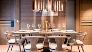 A dining area with a wooden table set for six, surrounded by six chairs with cushioned seats. - Six Senses Residences Courchevel (Courchevel)