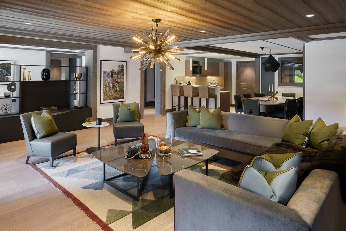 Een moderne woonkamer met een bank, fauteuils, een salontafel en een eethoek met een tafel en stoelen.
