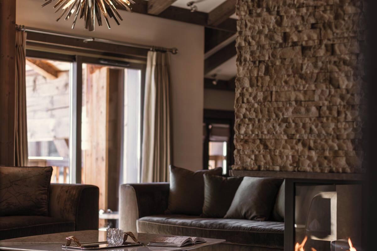Een moderne woonkamer met een stenen muur, een open haard en een bijzondere plafondlamp.