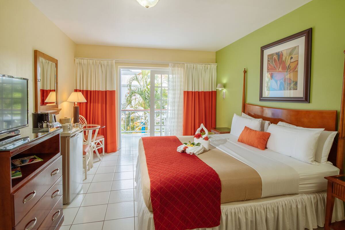 A hotel room with a bed, a desk with a computer, a TV, and a view of the outdoors.
