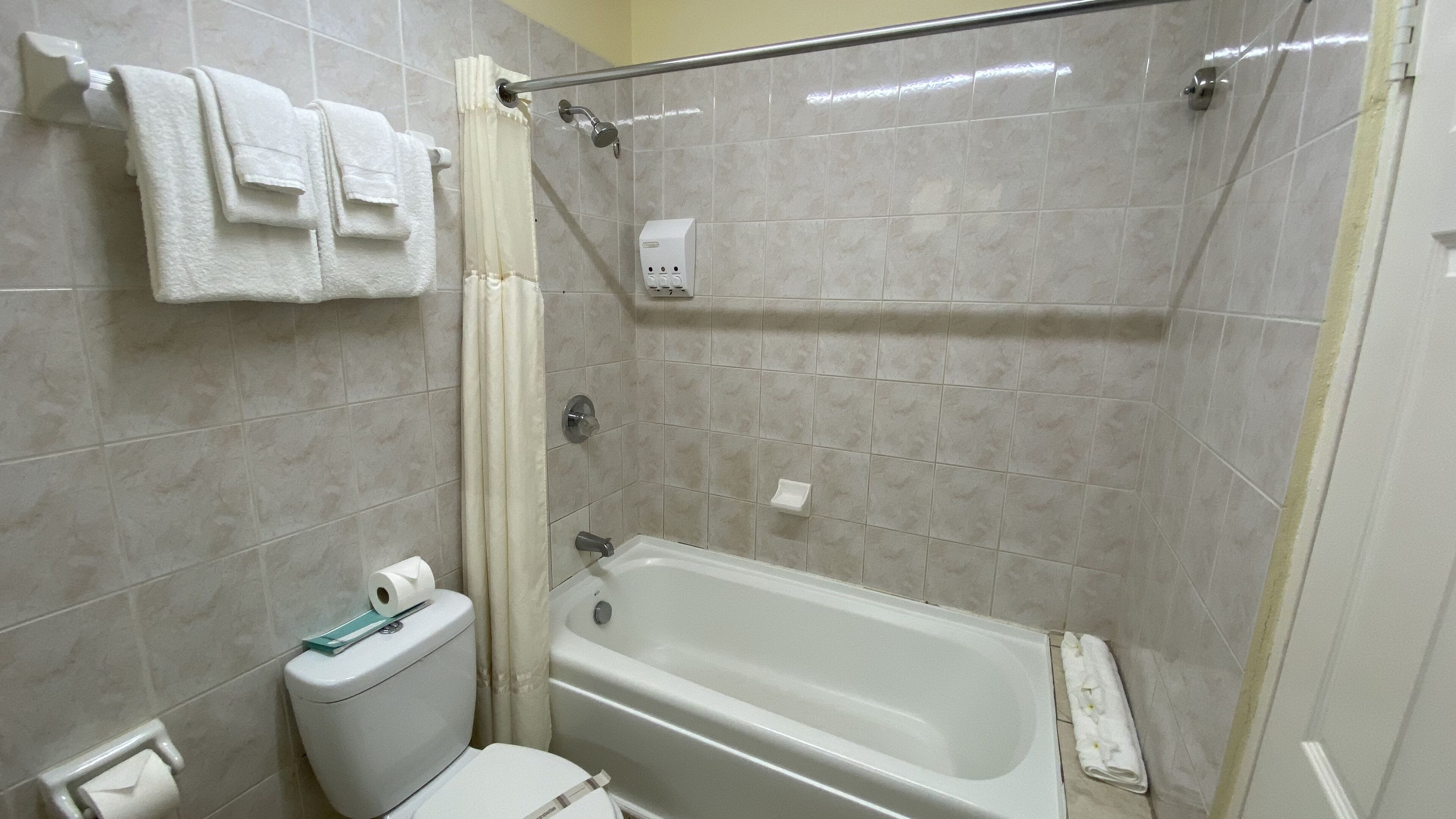Un baño con bañera, inodoro y cortina de ducha.