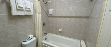 Un baño con bañera, inodoro y cortina de ducha.