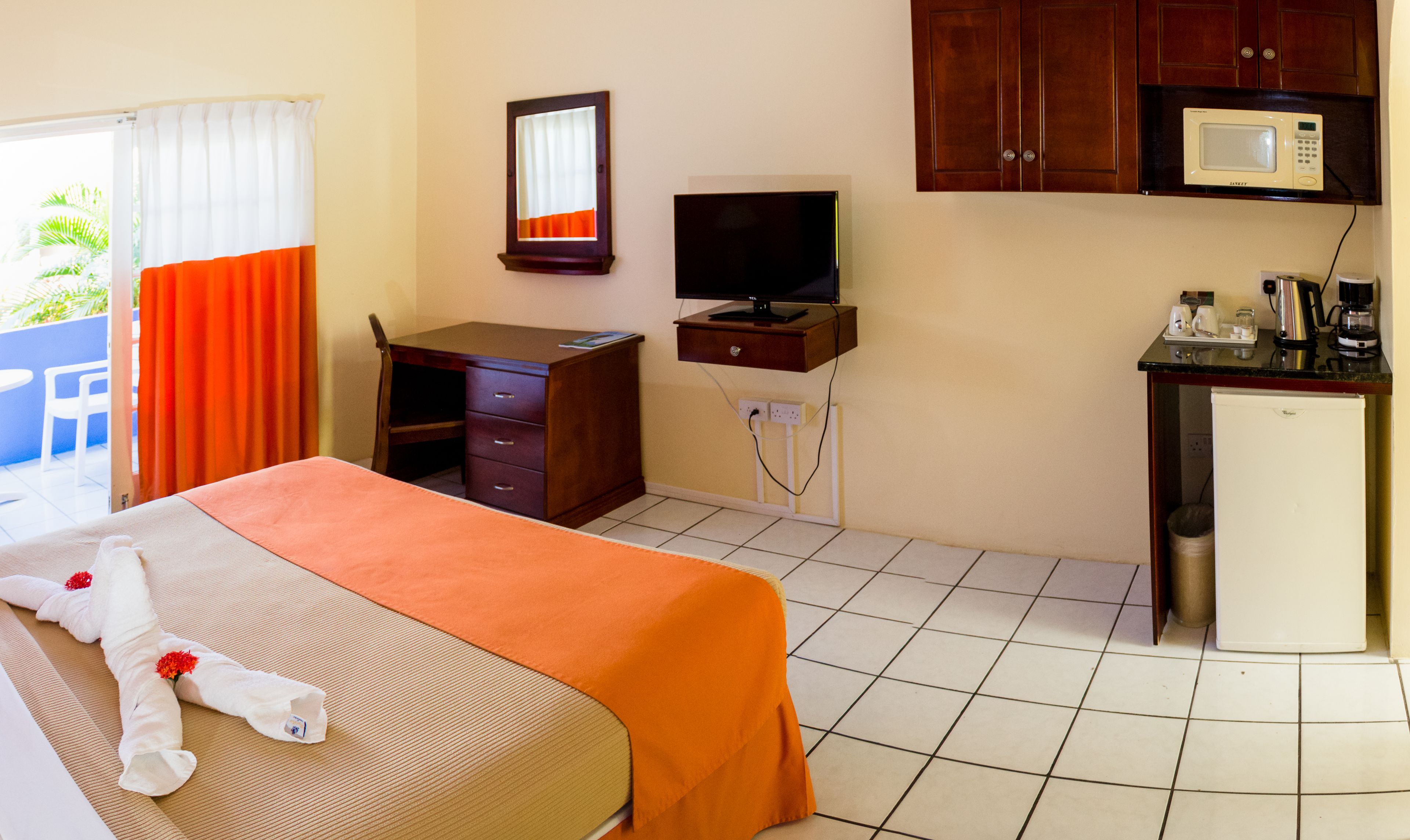 Hotelkamer met een bed, bureau, televisie, magnetron en koelkast.