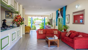 A reception area with a receptionist desk, a red sofa, a coffee table, and a view of the outdoor area.