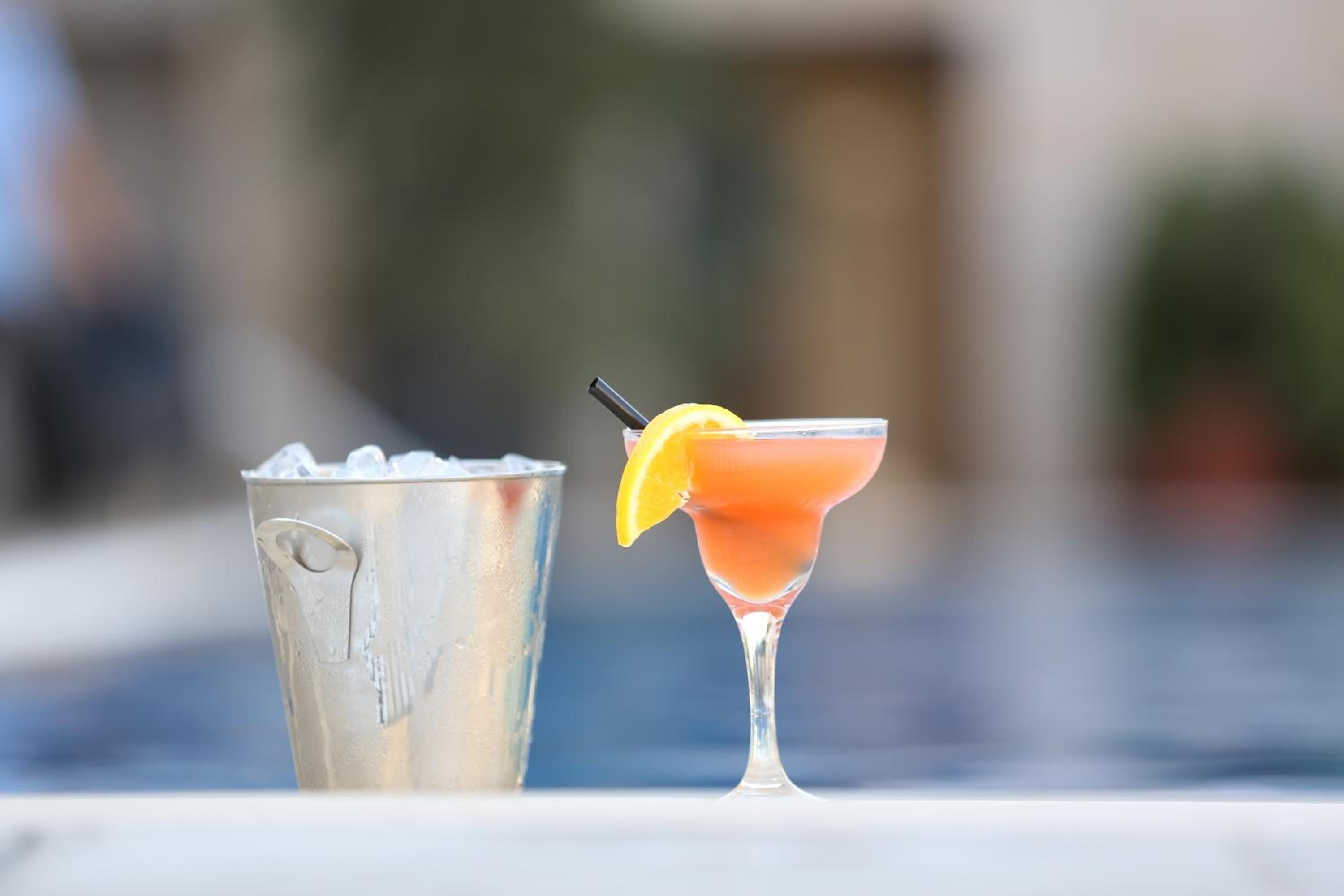 A cocktail glass with a lemon garnish and a metal bucket filled with ice.