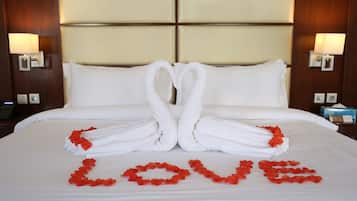 A hotel room with a bed, two wall-mounted lamps, and a bedside table with a phone and a tissue box.