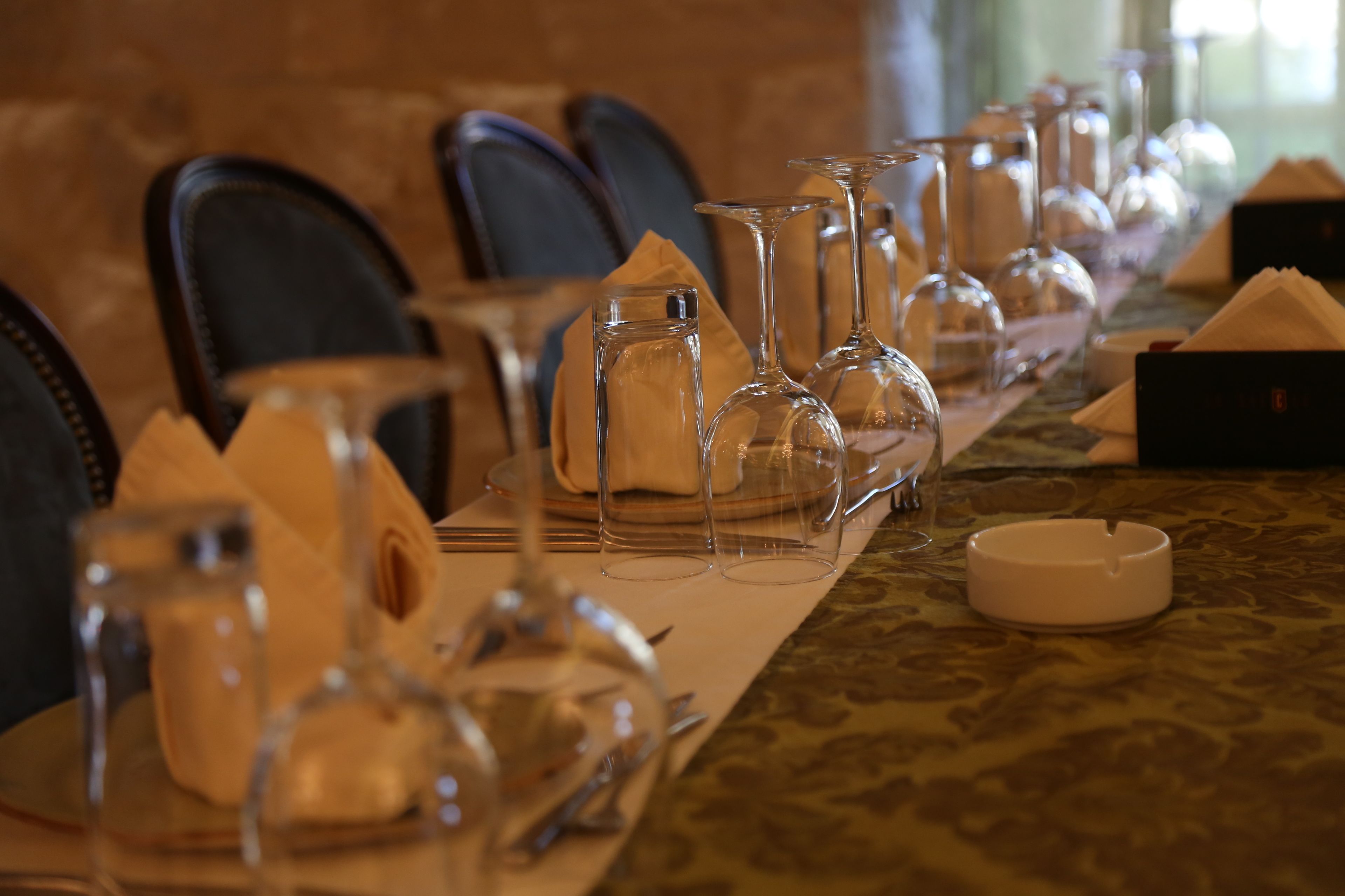 A dining table set with glassware, napkins, and a candle holder.